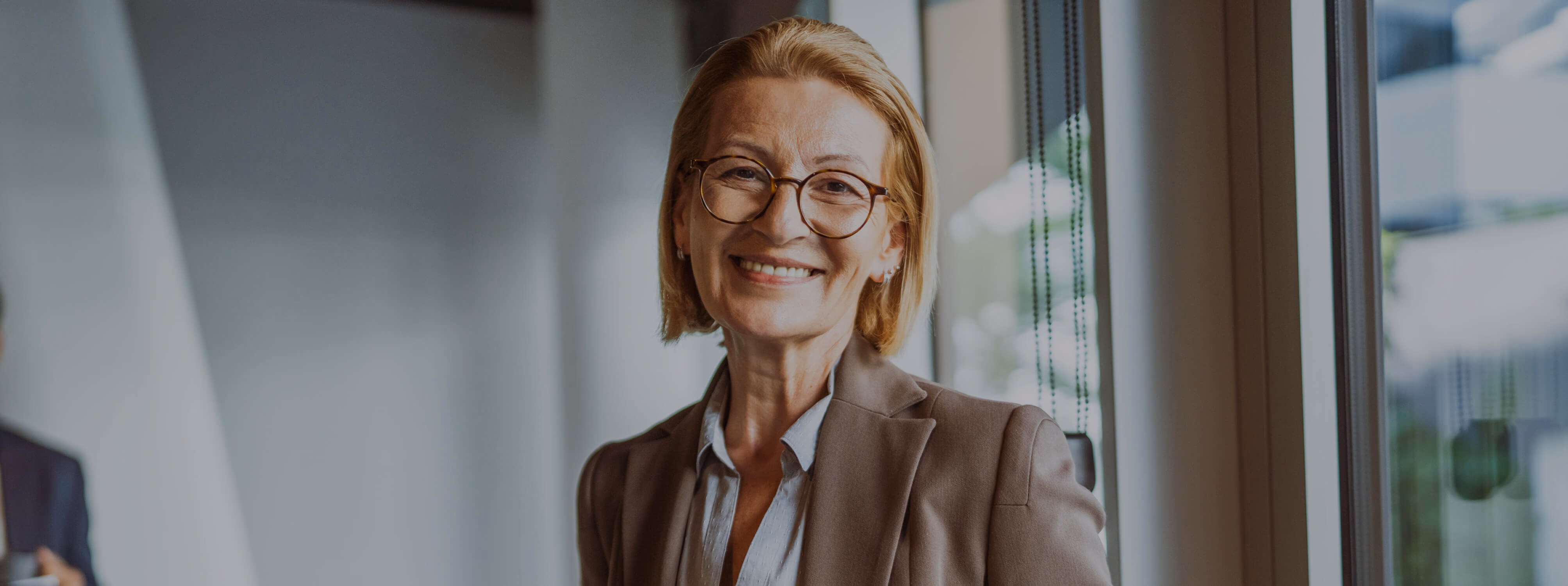 Confident businesswoman wearing glasses and a blazer, smiling warmly