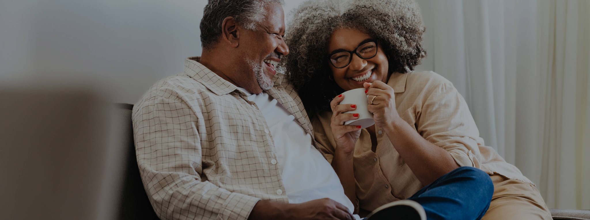 Happy couple sitting together, smiling while looking at documents
